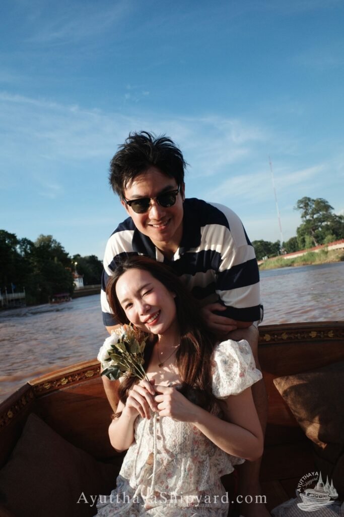 Ayutthaya boat tour, romantic river cruise, traditional Thai dress, Chao Phraya River, Ayutthaya Shipyard Couple smiling on Ayutthaya boat tour with flowers, romantic river cruise on Chao Phraya River by Ayutthaya Shipyard