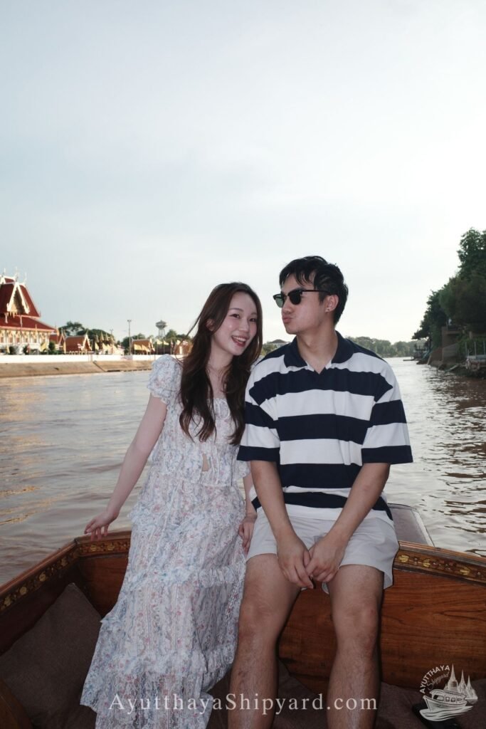 Ayutthaya boat tour, romantic river cruise, traditional Thai dress, Chao Phraya River, Ayutthaya Shipyard Couple smiling on Ayutthaya boat tour with flowers, romantic river cruise on Chao Phraya River by Ayutthaya Shipyard