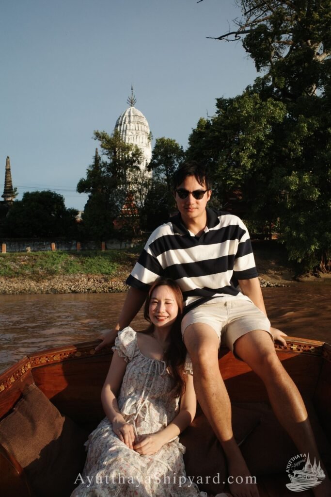 Ayutthaya boat tour, romantic river cruise, traditional Thai dress, Chao Phraya River, Ayutthaya Shipyard Couple smiling on Ayutthaya boat tour with flowers, romantic river cruise on Chao Phraya River by Ayutthaya Shipyard