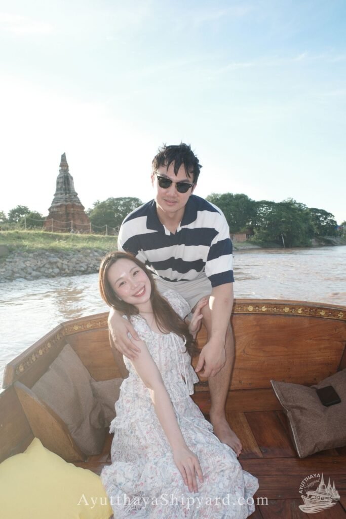 Ayutthaya boat tour, romantic river cruise, traditional Thai dress, Chao Phraya River, Ayutthaya Shipyard Couple smiling on Ayutthaya boat tour with flowers, romantic river cruise on Chao Phraya River by Ayutthaya Shipyard
